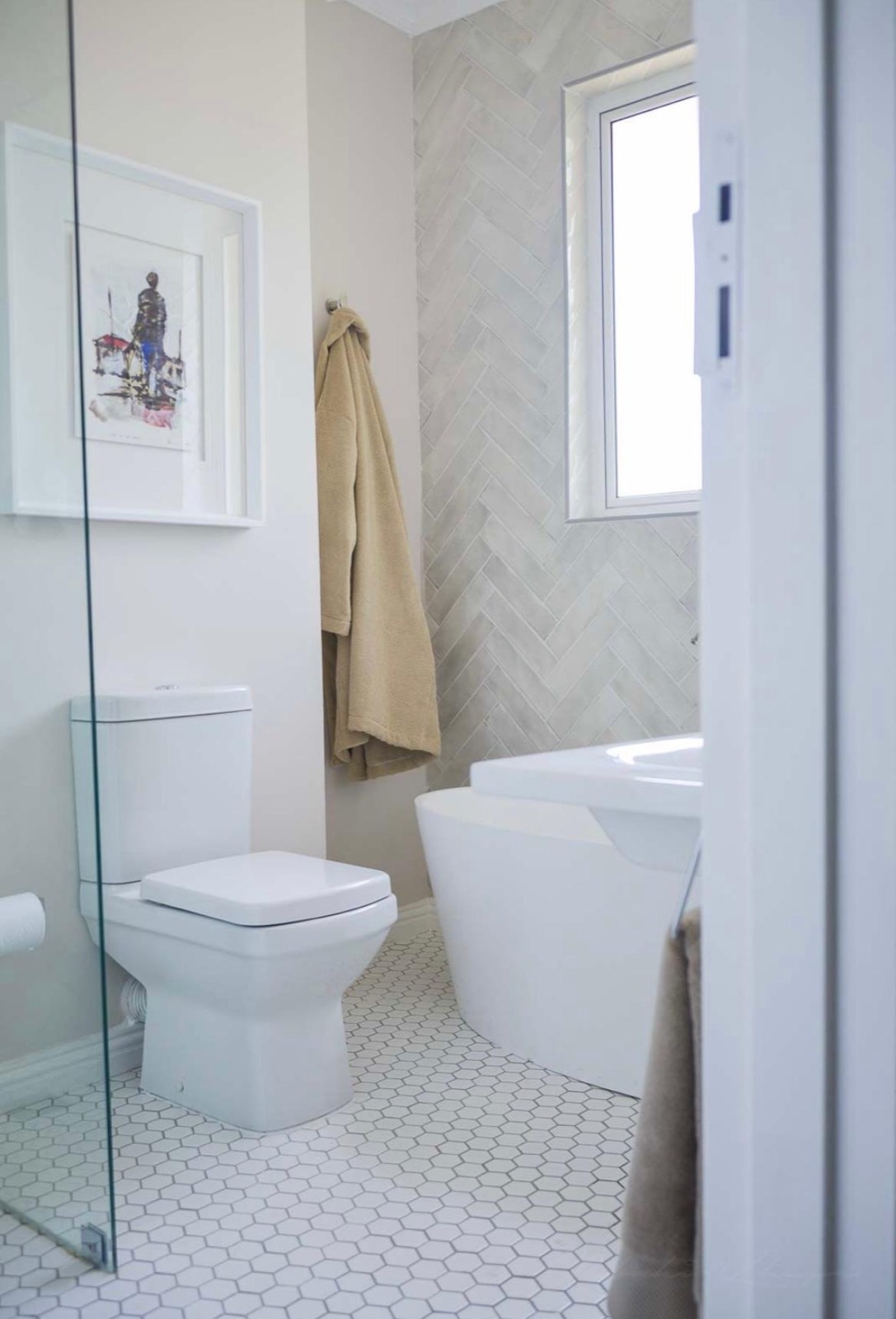 The bedroom's ensuite bathroom, with a freestanding bath and herringbone tile