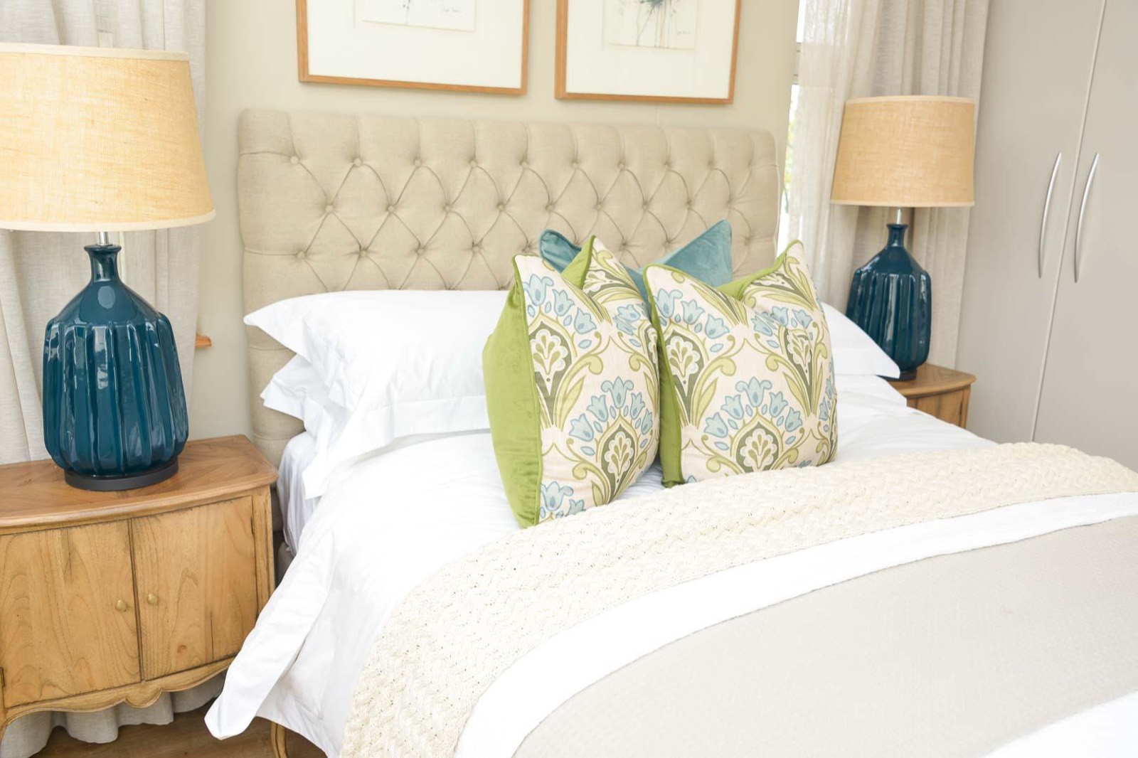 The bedroom, with a buttoned headboard, queen bed and scatter cushions