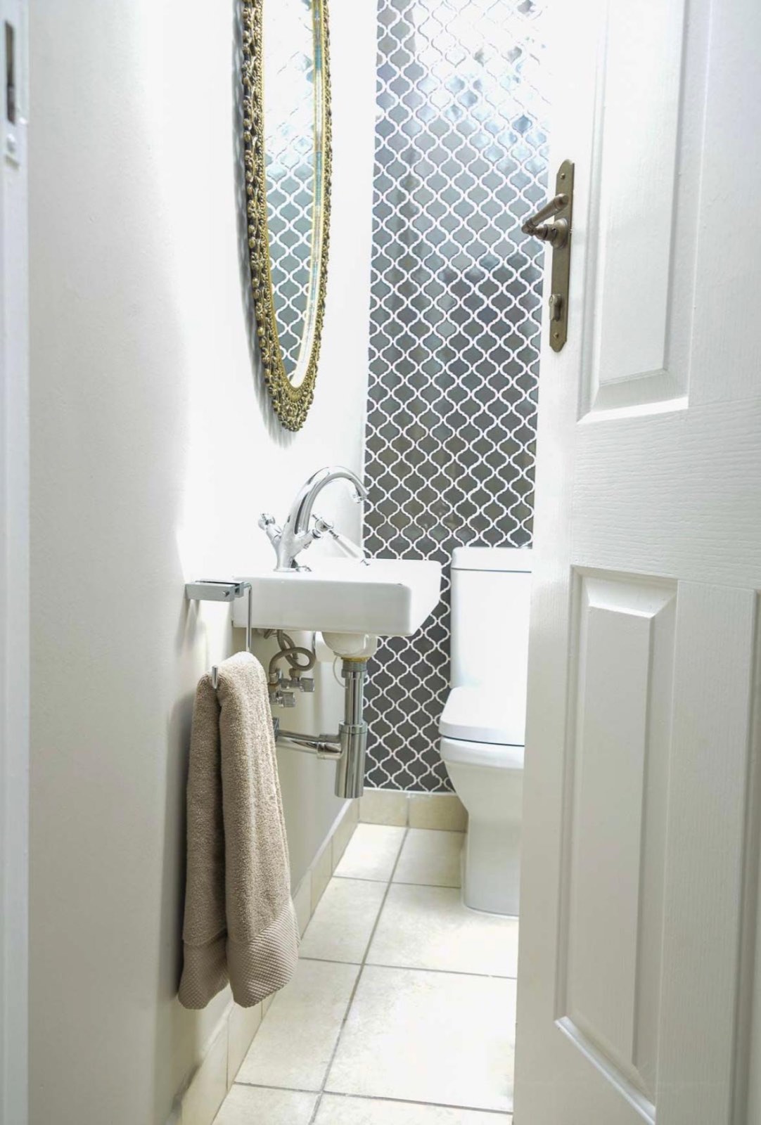 The guest loo, with grey arabesque tile and a gilt mirror