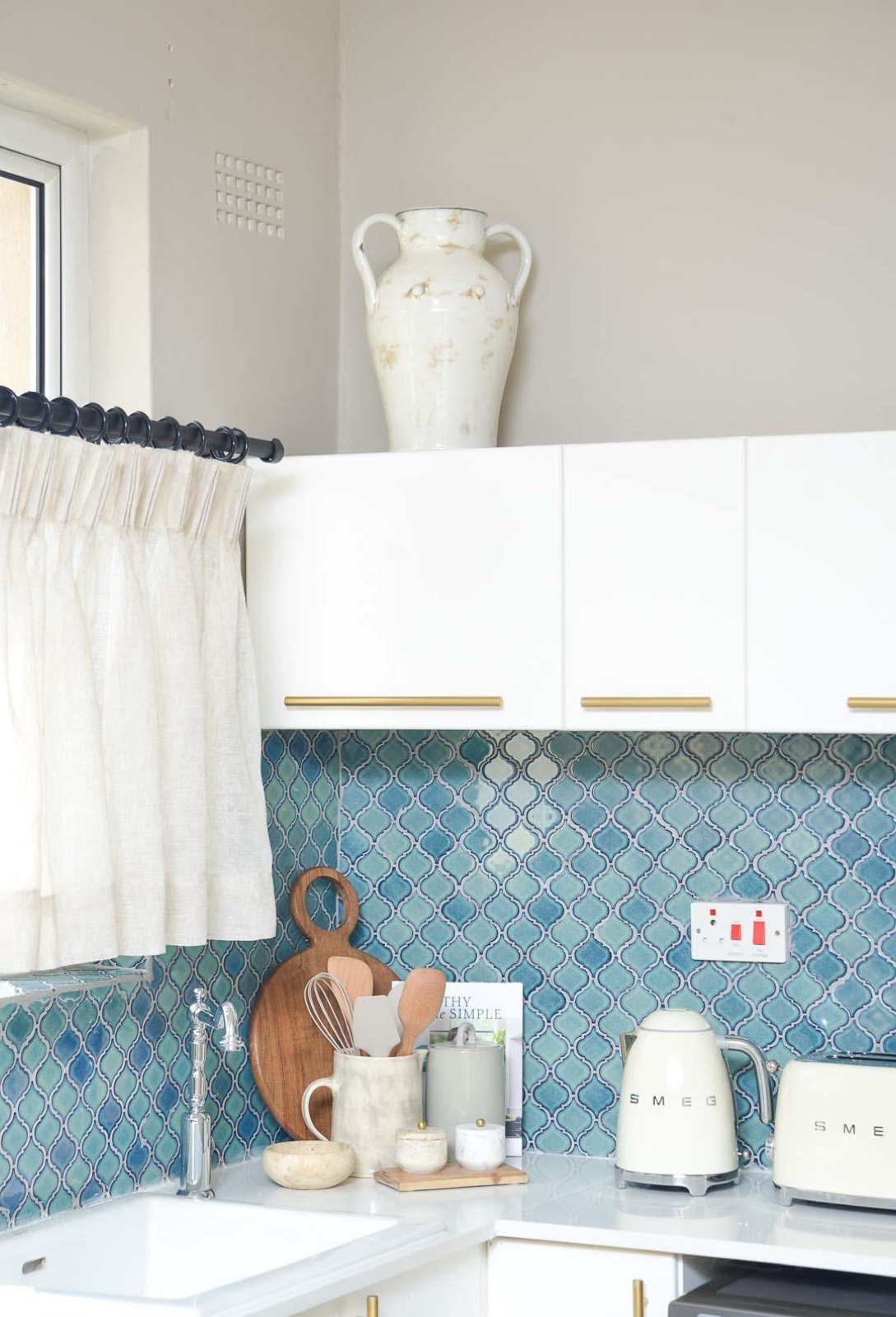 The kitchen, with hand-glazed teal tile, cream appliances and white cupboards